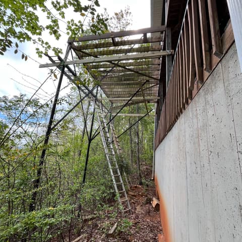New deck frame seen from below, ladder against the house wall