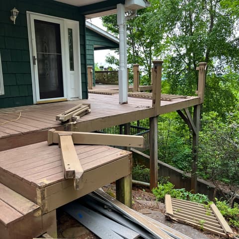 Old deck stripped back to its frame beside a green house