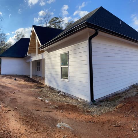 Finished house in white with a black roof under a clear blue sky