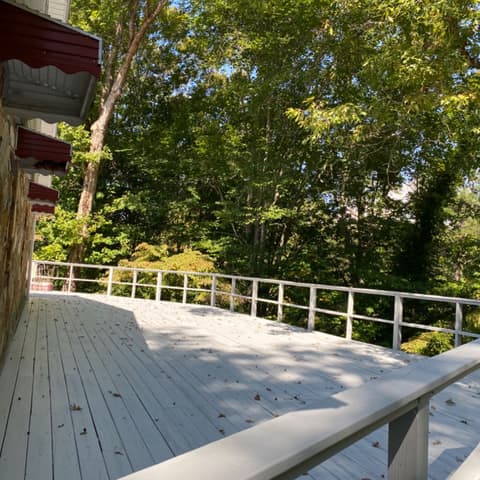 Grey-painted deck with a white rail on a wooded lot